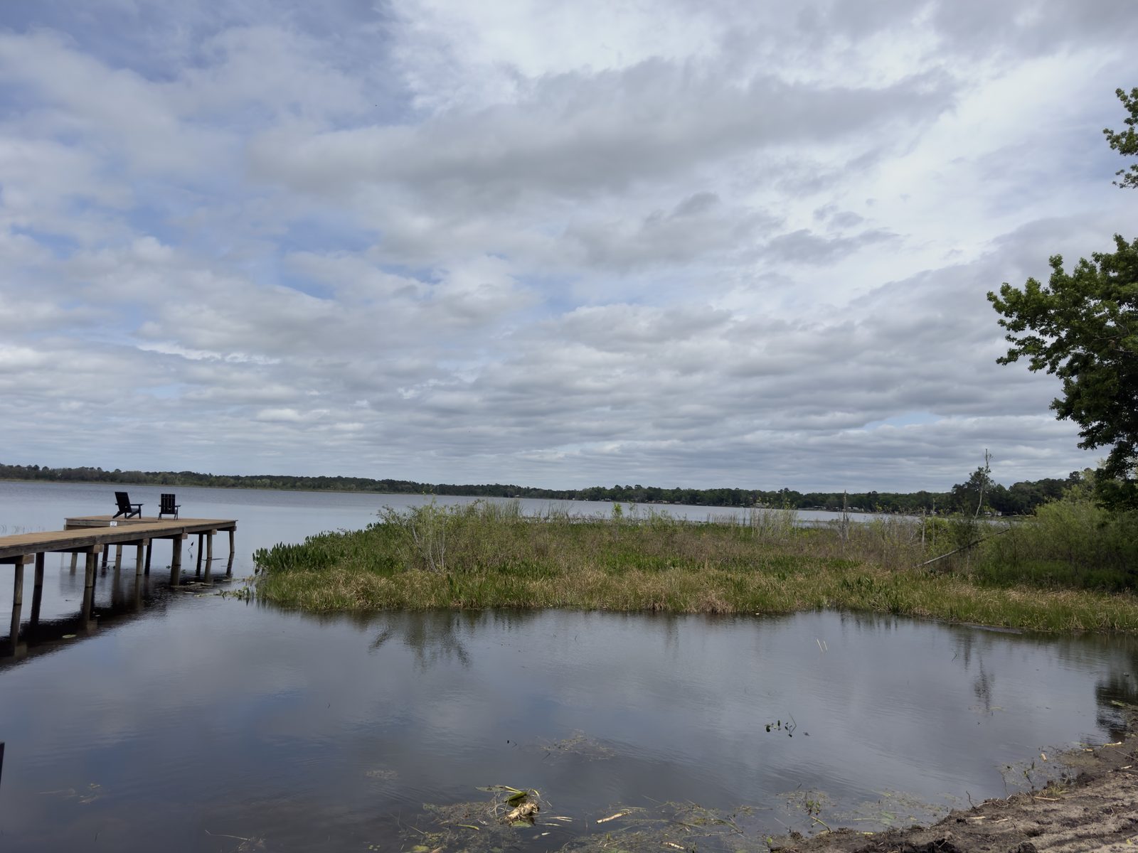 Wooden dock with two chairs on a calm lake near Interlachen in Putnam County, Florida, under a cloudy sky